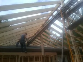 Rafters going up over a new addition with a worker on the wall in Henderson